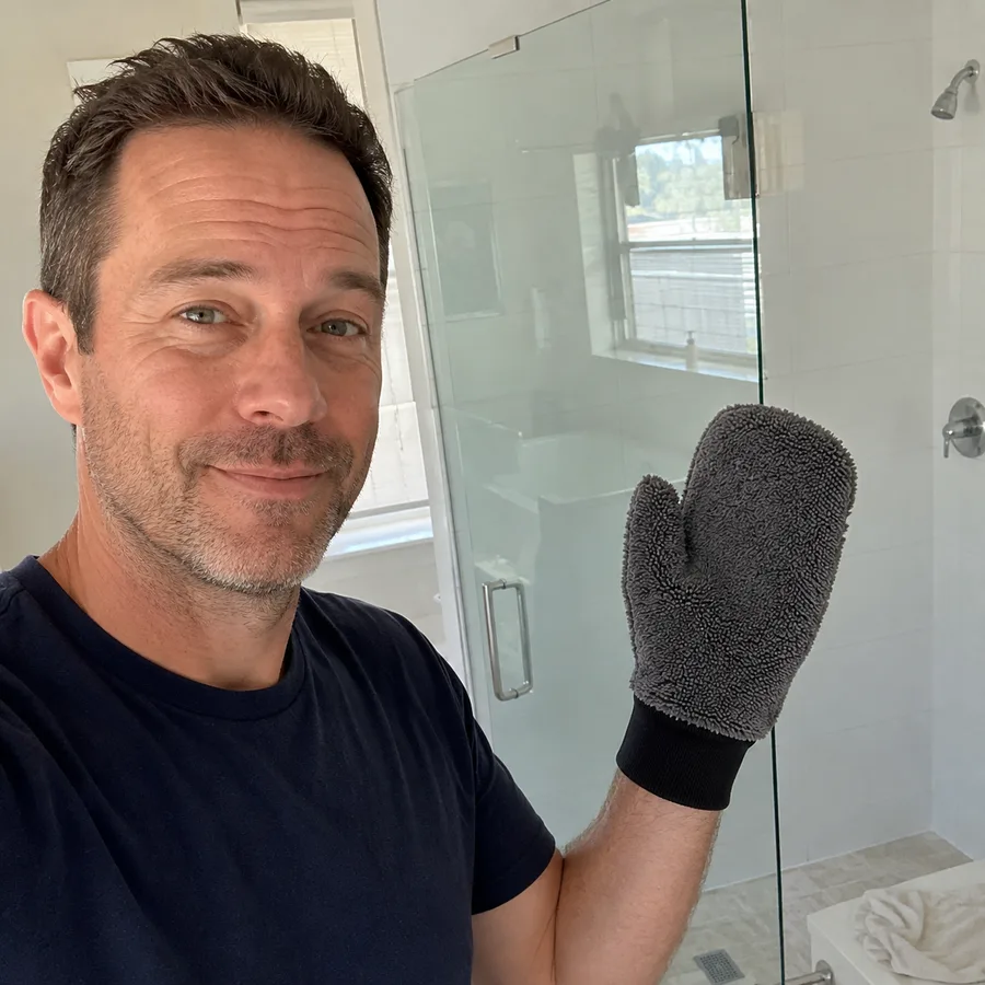 Marcus holding the GloveIt mitt next to a clear shower screen