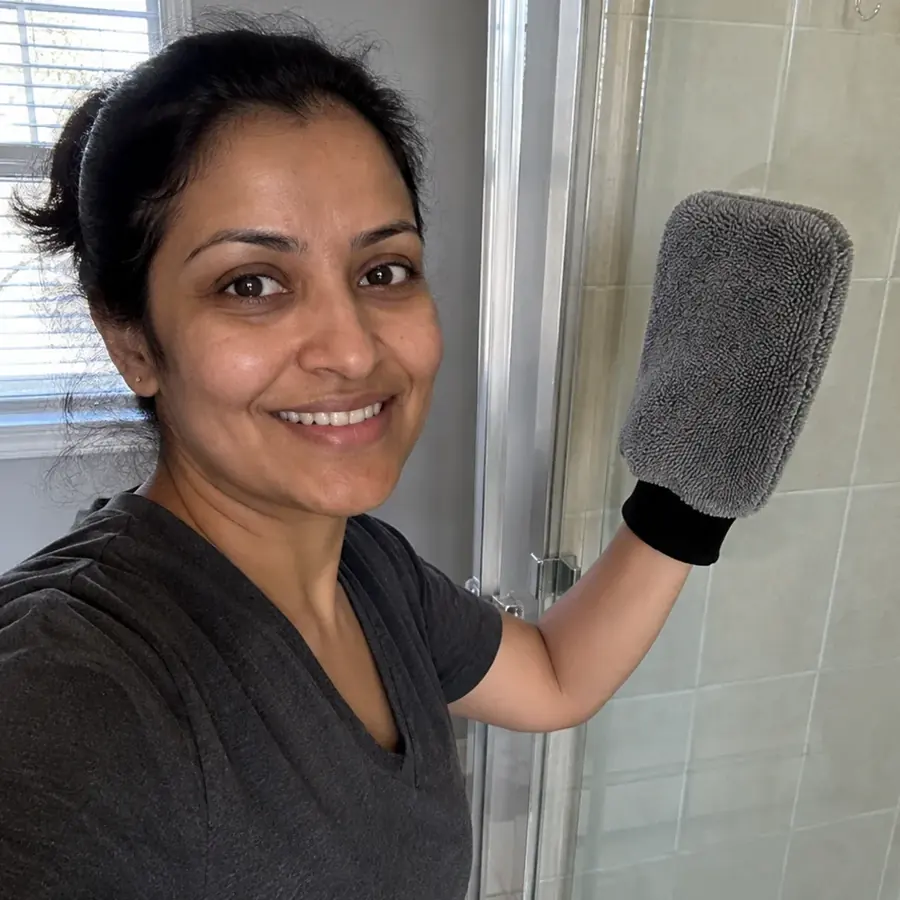 Priya wearing the GloveIt mitt beside her clear shower door
